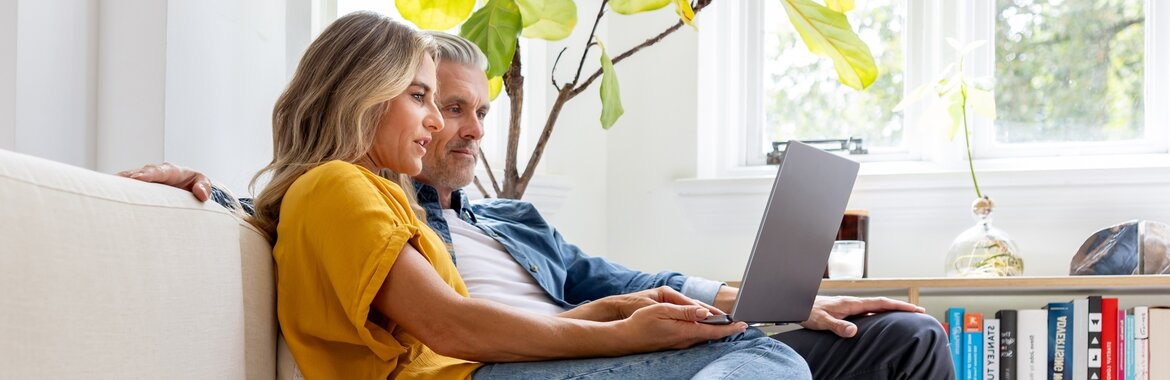 Paar zu Hause, das zusammen auf einen Laptop schaut